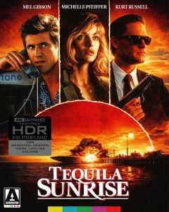 Movie poster for “Tequila Sunrise” featuring Mel Gibson, Michelle Pfeiffer, and Kurt Russell, with a dramatic sunset, palm trees, and a cityscape in the background.