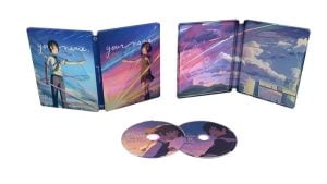 Two open steelbook cases for “Your Name.” are shown side by side with illustrated covers and interiors. Two matching discs with character artwork are placed in front of the cases.