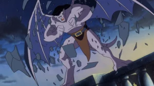 A winged gargoyle breaks free from stone as shards fly around, standing on a rooftop at night under a dark sky.