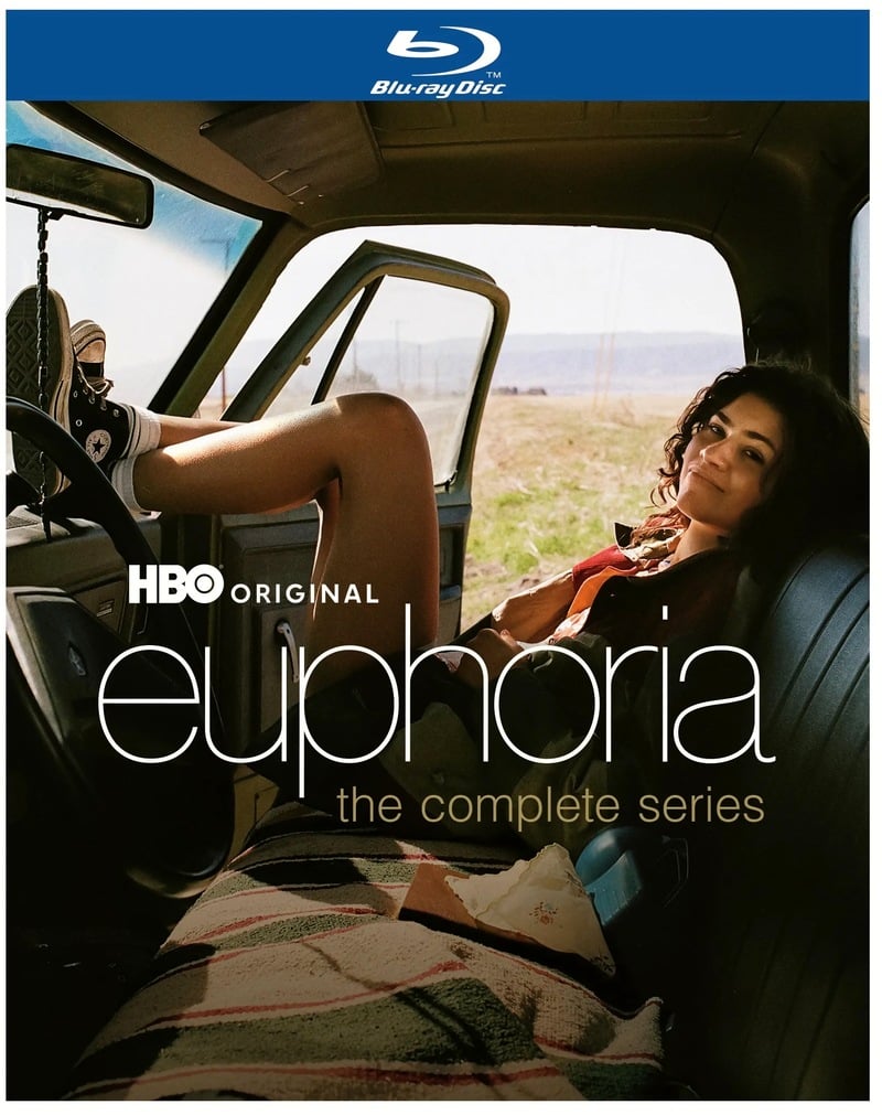 A woman relaxes in the front seat of a vehicle, with her feet up on the dashboard. The cover text reads: “HBO Original Euphoria: The Complete Series.”.