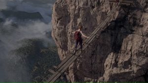 A person with a backpack walks carefully across a narrow, broken wooden bridge suspended high on a rocky mountain cliff.