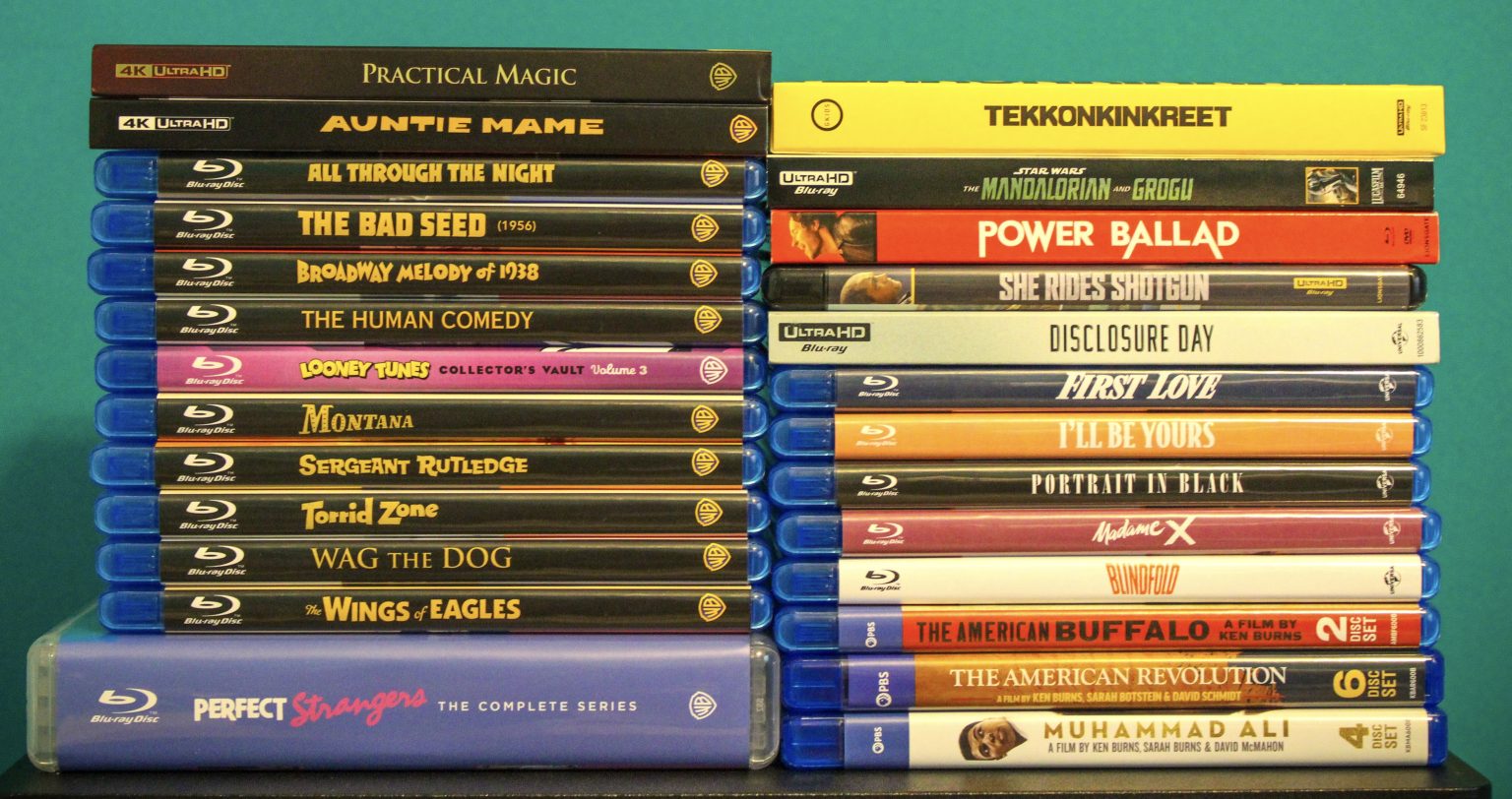 No Streaming Required: Physical Media Spotlight For The Week Of September 1st Stacked Blu-ray and DVD cases arranged in two columns against a blue background, showing a variety of film and TV titles in different genres.