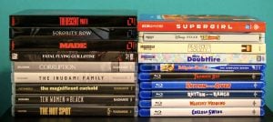 No Streaming Required: Physical Media Spotlight For The Week Of September 22nd Stacks of DVD and Blu-ray movie cases arranged side by side on a flat surface against a teal background.