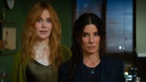 ‘Practical Magic 2’ Review: Familiar Spells Still Work Their Magic Two women stand indoors; one with long red hair in a green outfit, the other with dark hair in a braid and a black outfit. They face forward against a backdrop of green walls and window blinds.