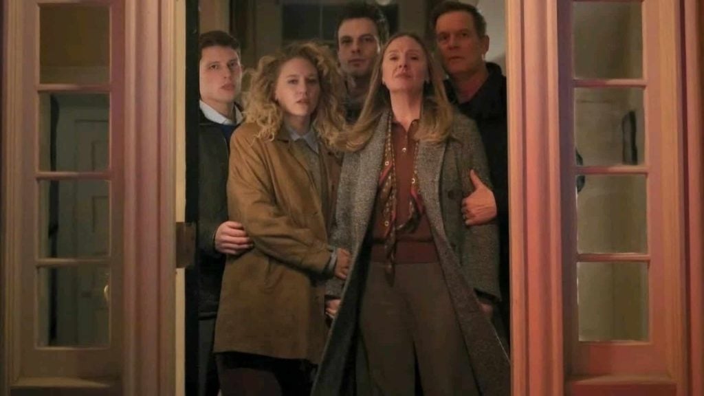 ‘Line of Fire’ Season 1 Review: Your Typical Network Drama With An Engaging Mystery Five people stand closely together in a doorway, looking outward with serious expressions. The group includes three young adults and two older adults, all wearing coats or jackets.
