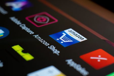 Close-up of a tablet screen showing the Amazon shopping app icon among other application icons.