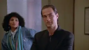 A man in a black blazer and a woman in a denim jacket standing together.