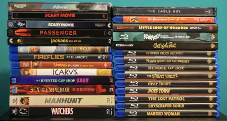 No Streaming Required: Physical Media Spotlight For The Week Of October 13th Two stacks of Blu-ray and 4K Ultra HD movie cases on a shelf.