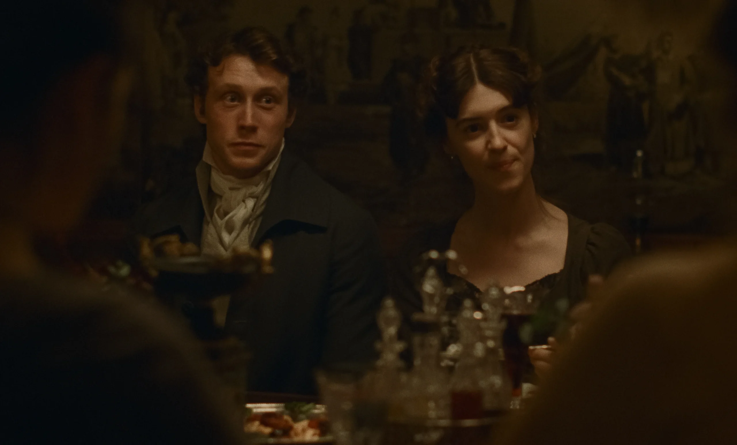 A man and woman in historical attire sitting at a dinner table.