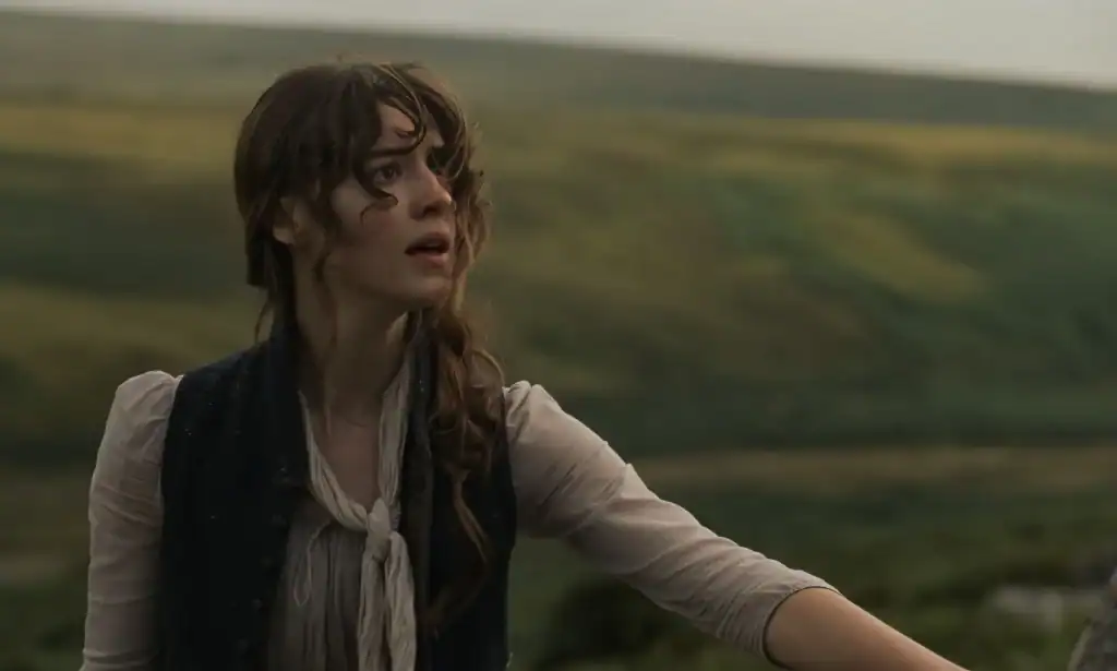 A young woman with a concerned expression looking off-camera against a backdrop of rolling hills.