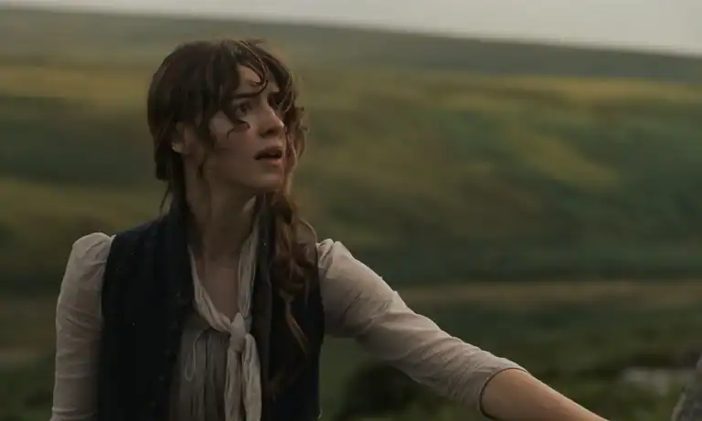 A young woman with a concerned expression looking off-camera against a backdrop of rolling hills.