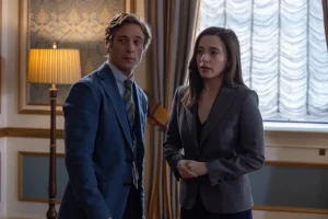 ‘The Social Reckoning’ Review – A Toothless Political Thriller That Thoroughly Distrusts Its Audience A man in a suit and a woman in a blazer standing and looking toward the side in a formal room.