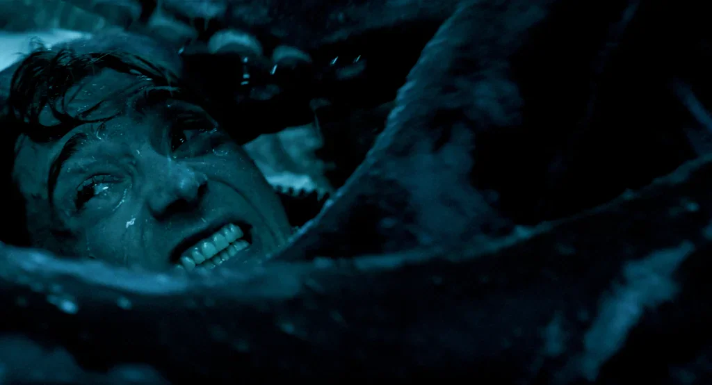A terrified man with a distressed expression surrounded by large, dark tentacles.