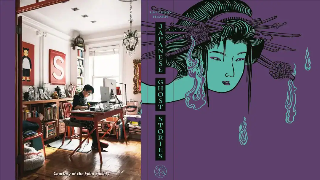 A person works at a desk in a home office next to the cover of the book Japanese Ghost Stories by Lafcadio Hearn.