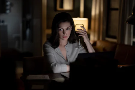 ‘Verity’ Review – A Twisty Thriller With Less Bite Than The Book A woman sits at a desk working on a laptop at night, holding a glass of red wine.